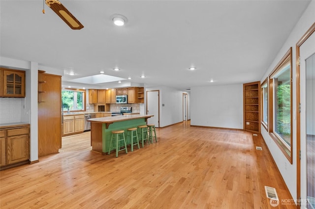 4205 Delphi Rd SW, Olympia, WA 98512 - kitchen with open shelves, appliances with stainless steel finishes, a breakfast bar, backsplash, and light countertops