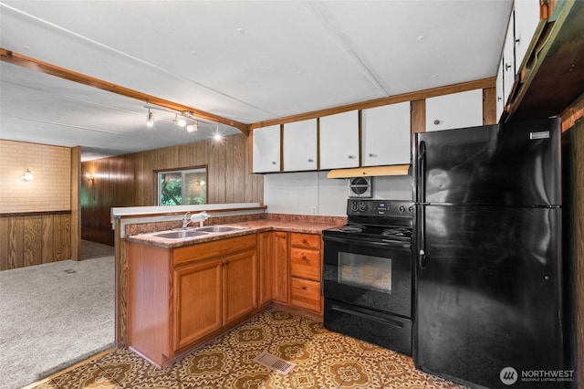 4205 Delphi Rd SW, Olympia, WA 98512 - kitchen featuring black appliances, wooden walls, a sink, a peninsula, and brown cabinets