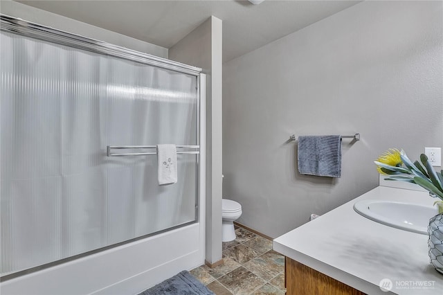 56065608 76th Street Ct E, Puyallup, WA 98371 - full bath with vanity, toilet, shower / bath combination with glass door, stone finish flooring, and baseboards