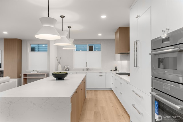 238 4th Ave Unit 101, Kirkland, WA 98033 - kitchen featuring modern cabinets, light wood-style floors, light countertops, recessed lighting, and pendant lighting