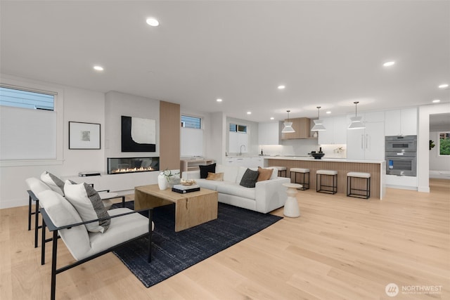 238 4th Ave Unit 101, Kirkland, WA 98033 - living area featuring light wood finished floors, recessed lighting, a glass covered fireplace, and healthy amount of natural light