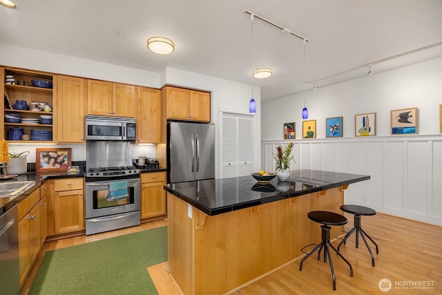 156 Hall Brothers Loop NE Unit 201, Bainbridge Island, WA 98110 - kitchen with stainless steel appliances, light wood finished floors, a breakfast bar, track lighting, and wainscoting