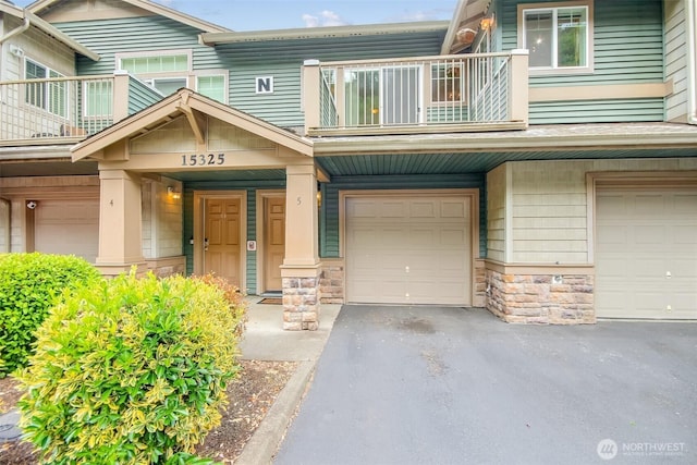 15325 SE 155th Pl Unit N5, Renton, WA 98058 - doorway to property with a balcony, an attached garage, stone siding, and driveway
