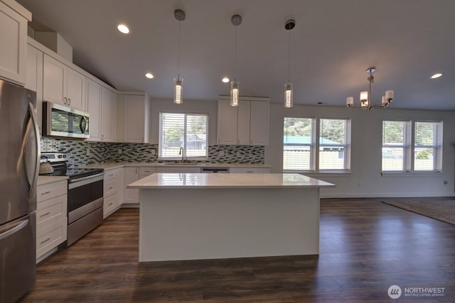 2201 303rd Pl, Ocean Park, WA 98640 - kitchen with stainless steel appliances, a sink, light countertops, a center island, and decorative backsplash