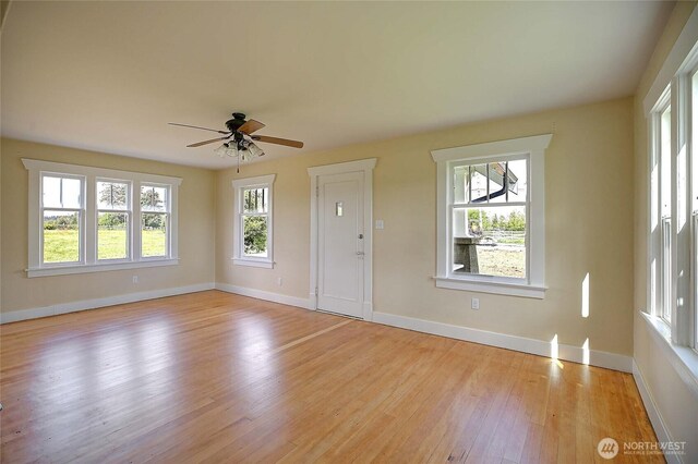 27120 36th Ave NW, Stanwood, WA 98292 - unfurnished living room with light wood finished floors, a ceiling fan, and baseboards