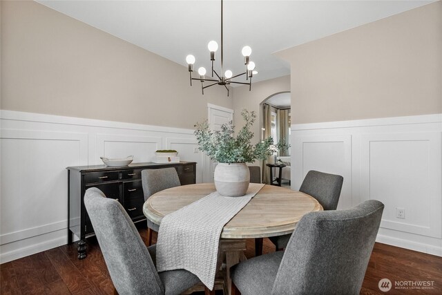 11226 Borgen Loop, Gig Harbor, WA 98332 - dining space with a chandelier, dark wood-style flooring, a decorative wall, a wainscoted wall, and arched walkways