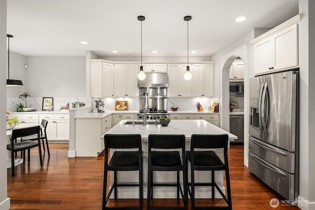 5102 S Frontenac St, Seattle, WA 98118 - kitchen featuring stainless steel appliances, under cabinet range hood, an island with sink, tasteful backsplash, and dark wood-style flooring