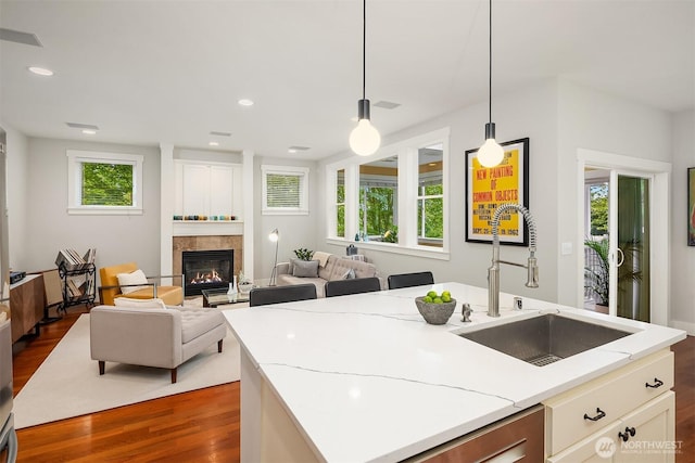 5102 S Frontenac St, Seattle, WA 98118 - kitchen with a sink, dark wood-type flooring, decorative light fixtures, a tile fireplace, and light stone counters