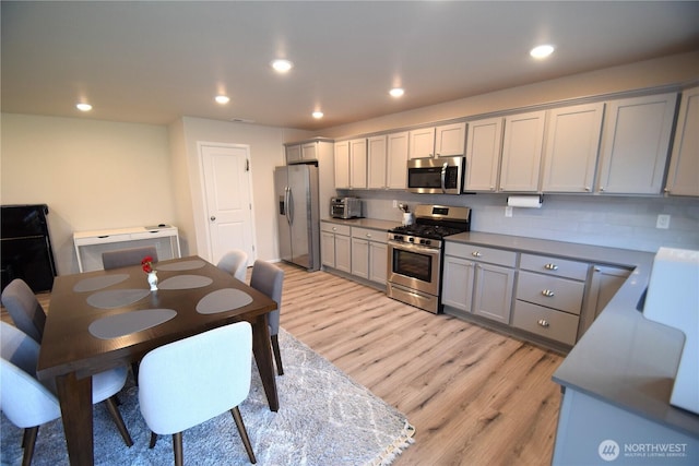 kitchen featuring appliances with stainless steel finishes, gray cabinetry, light wood finished floors, backsplash, and recessed lighting