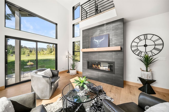 91 Pebble Beach Dr, Cle Elum, WA 98922 - living area featuring a tiled fireplace, wood finished floors, a high ceiling, and baseboards