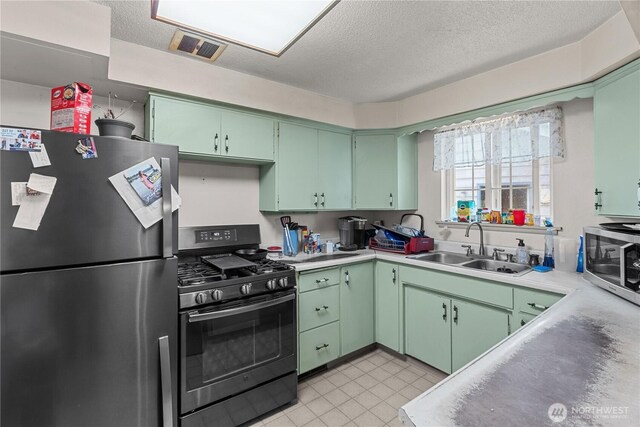 9712 126th St E, Puyallup, WA 98373 - kitchen featuring stainless steel appliances, green cabinets, a textured ceiling, and a sink