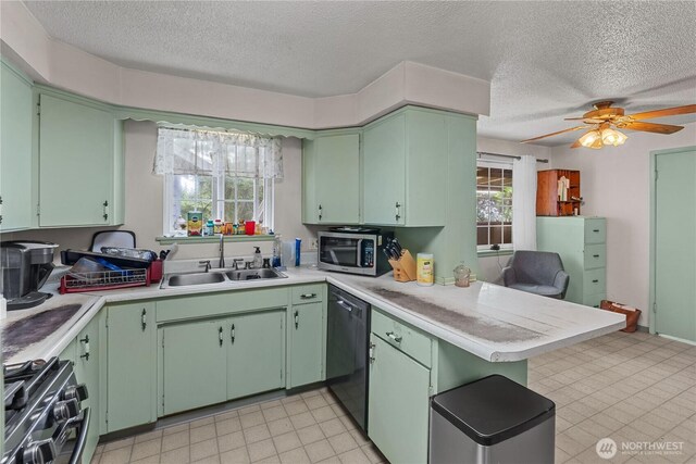 9712 126th St E, Puyallup, WA 98373 - kitchen featuring appliances with stainless steel finishes, a sink, a peninsula, a textured ceiling, and light countertops