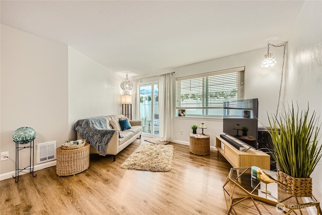 3045 20th Ave W Unit 108, Seattle, WA 98199 - living room featuring wood finished floors, a chandelier, and baseboards