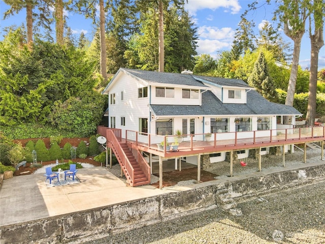 8609 E Caraway Rd, Port Orchard, WA 98366 - back of property with stairway, a patio, a wooden deck, view of scattered trees, and roof with shingles
