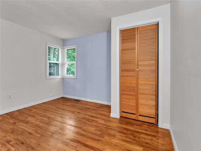 14746 26th Ave NE, Shoreline, WA 98155 - unfurnished bedroom featuring light wood-style floors, a closet, a textured ceiling, and baseboards