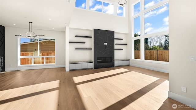 17109 NE 16th Pl, Bellevue, WA 98008 - unfurnished living room featuring a chandelier, wood finished floors, recessed lighting, baseboards, and a towering ceiling