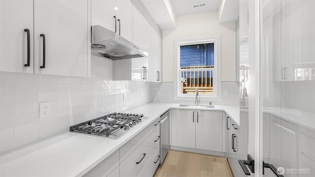 17109 NE 16th Pl, Bellevue, WA 98008 - kitchen with under cabinet range hood, appliances with stainless steel finishes, a sink, and white cabinets