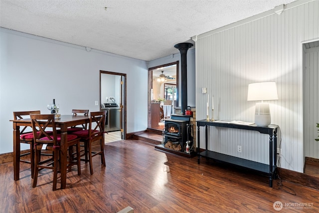17009 15th Ave E, Spanaway, WA 98387 - dining room featuring a wood stove, wood finished floors, a textured ceiling, and baseboards