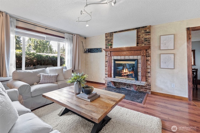17009 15th Ave E, Spanaway, WA 98387 - living area featuring wood finished floors, a textured ceiling, a brick fireplace, and baseboards
