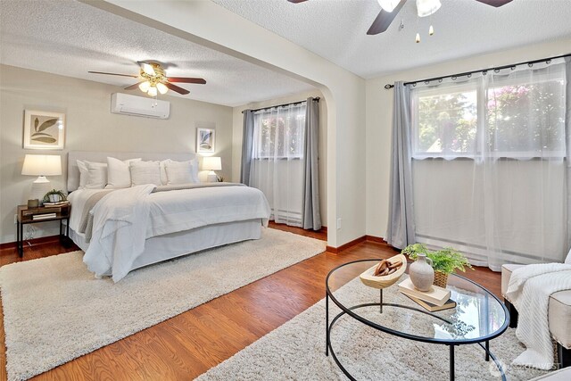17009 15th Ave E, Spanaway, WA 98387 - bedroom featuring a wall mounted AC, a textured ceiling, baseboards, wood finished floors, and ceiling fan