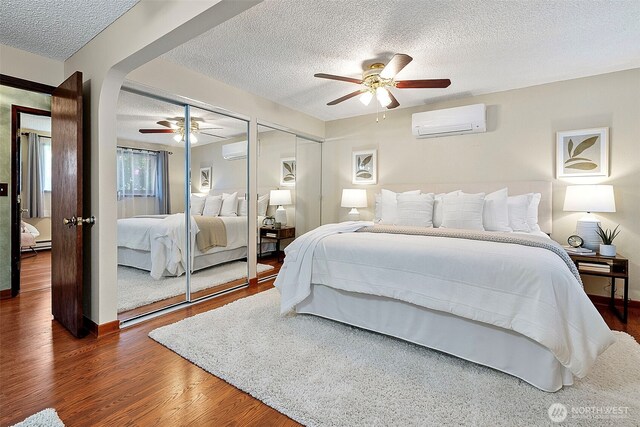17009 15th Ave E, Spanaway, WA 98387 - bedroom with an AC wall unit, a textured ceiling, wood finished floors, and multiple closets