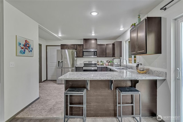 13218 197th St E, Graham, WA 98338 - kitchen featuring appliances with stainless steel finishes, dark brown cabinetry, a peninsula, a sink, and a breakfast bar area
