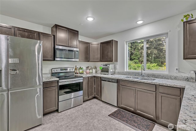 13218 197th St E, Graham, WA 98338 - kitchen with appliances with stainless steel finishes, a sink, dark brown cabinets, light stone countertops, and recessed lighting