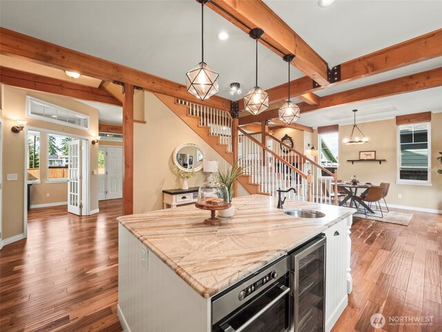 20409 70th St E, Bonney Lake, WA 98391 - kitchen featuring a sink, wine cooler, beam ceiling, wood finished floors, and baseboards