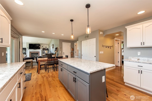 1063 Tamarack Ln, Port Angeles, WA 98362 - kitchen featuring gray cabinetry, a kitchen island, light wood finished floors, pendant lighting, and a fireplace