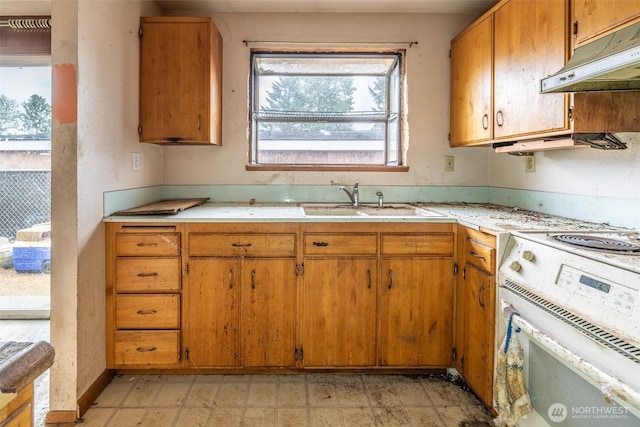 1216 E 70th St, Tacoma, WA 98404 - kitchen featuring under cabinet range hood, white electric range, light countertops, a sink, and brown cabinets
