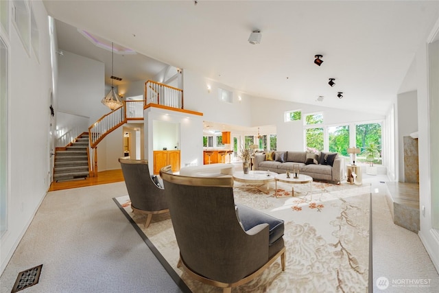 5501 55th St SE, Auburn, WA 98092 - living room featuring high vaulted ceiling, stairs, light colored carpet, and baseboards