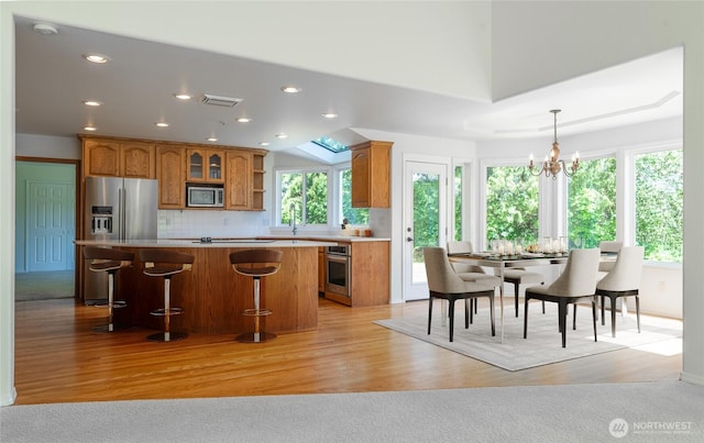 5501 55th St SE, Auburn, WA 98092 - kitchen featuring stainless steel appliances, brown cabinets, a center island, light countertops, and tasteful backsplash