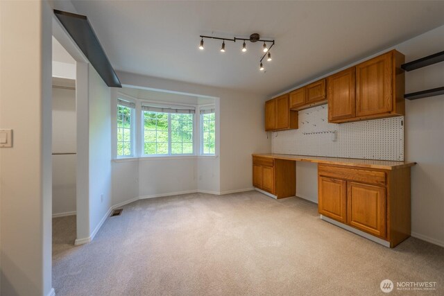 5501 55th St SE, Auburn, WA 98092 - kitchen with brown cabinetry, light carpet, baseboards, light countertops, and tasteful backsplash
