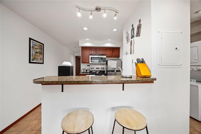 322 W Woodin Ave Unit 632, Chelan, WA 98816 - kitchen with stainless steel appliances, stacked washer / drying machine, a kitchen breakfast bar, a peninsula, and dark countertops