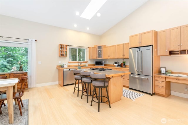 137 Sudden Valley Dr, Bellingham, WA 98229 - kitchen featuring appliances with stainless steel finishes, light brown cabinets, light wood finished floors, high vaulted ceiling, and glass insert cabinets