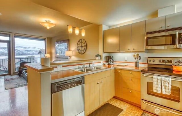 2220 W Woodin Ave Unit 303, Chelan, WA 98816 - kitchen with stainless steel appliances, a peninsula, a sink, light countertops, and decorative light fixtures
