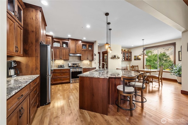 35 N Shore Dr, Orondo, WA 98843 - kitchen featuring appliances with stainless steel finishes, a sink, under cabinet range hood, light wood-style flooring, and brown cabinets
