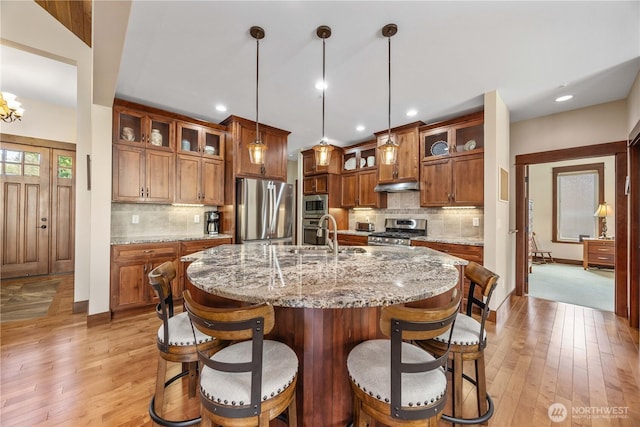 35 N Shore Dr, Orondo, WA 98843 - kitchen featuring appliances with stainless steel finishes, a sink, brown cabinetry, light wood-style floors, and tasteful backsplash