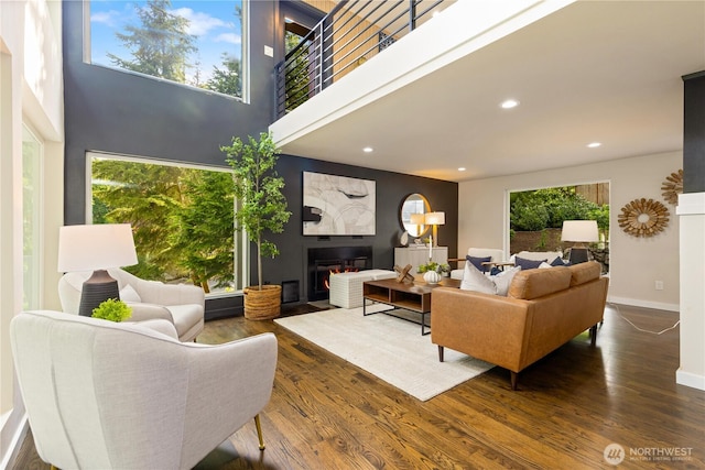 18510 NE 15th Pl, Bellevue, WA 98008 - living room featuring wood finished floors, recessed lighting, baseboards, a warm lit fireplace, and a towering ceiling