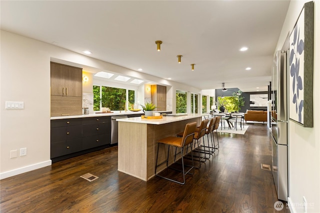 18510 NE 15th Pl, Bellevue, WA 98008 - kitchen featuring light countertops, dark wood-type flooring, a kitchen island, recessed lighting, and a breakfast bar