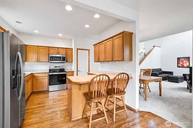 12032 38th Ave SE, Everett, WA 98208 - kitchen with appliances with stainless steel finishes, tile counters, a peninsula, a kitchen breakfast bar, and light wood-type flooring