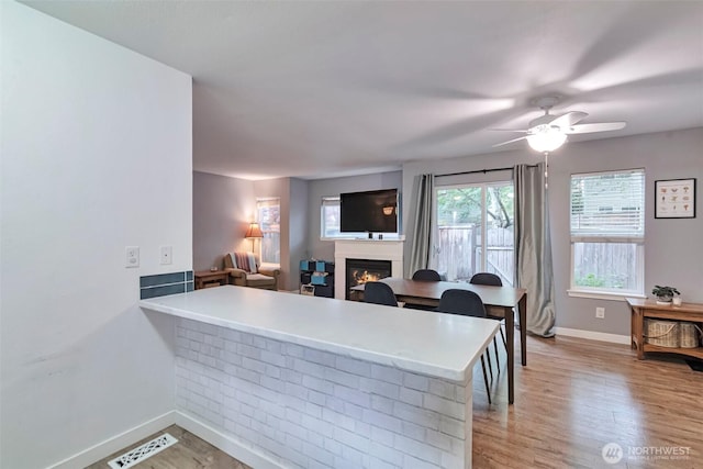 1131 115th St SW Unit M2, Everett, WA 98204 - kitchen with baseboards, a warm lit fireplace, a peninsula, light wood-type flooring, and light countertops