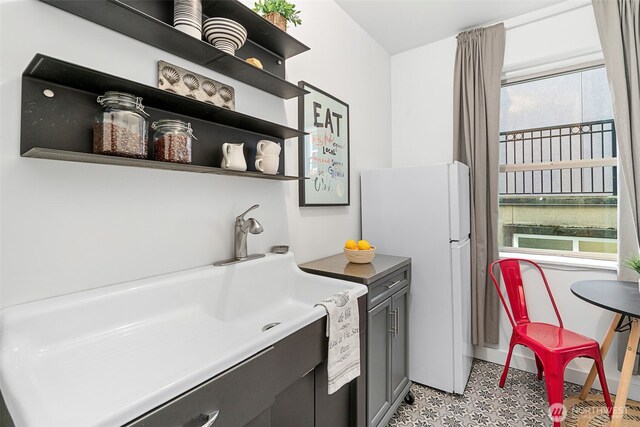 7 Harrison St Unit 26, Seattle, WA 98109 - kitchen with freestanding refrigerator, open shelves, gray cabinets, a sink, and light floors