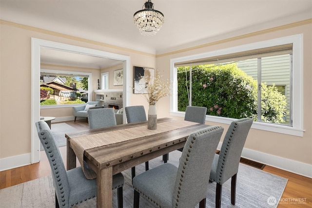 6813 17th Ave NE, Seattle, WA 98115 - dining area with a chandelier, baseboards, wood finished floors, and a warm lit fireplace