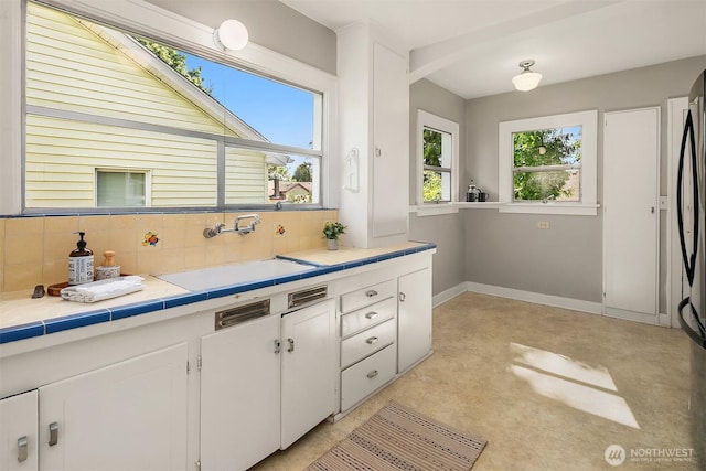 6813 17th Ave NE, Seattle, WA 98115 - kitchen with a sink, white cabinetry, baseboards, concrete floors, and backsplash