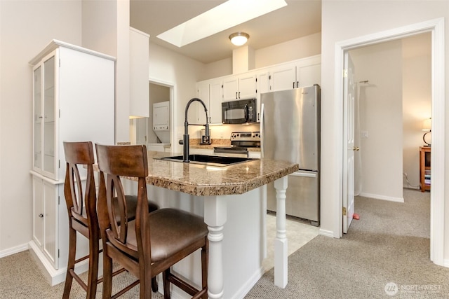 1002 9th Ave SE Unit C-201, Puyallup, WA 98372 - kitchen featuring stainless steel appliances, light colored carpet, a sink, and a breakfast bar area