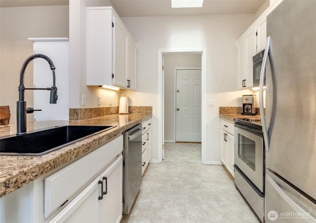 1002 9th Ave SE Unit C-201, Puyallup, WA 98372 - kitchen featuring stainless steel appliances, a sink, white cabinets, baseboards, and light flooring