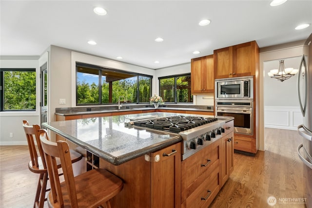 15102 93rd Pl NE, Bothell, WA 98011 - kitchen featuring appliances with stainless steel finishes, light wood-style floors, brown cabinets, a kitchen island, and a kitchen bar