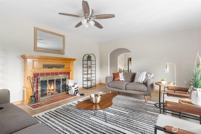 1001 Elm St, Centralia, WA 98531 - living area with wood finished floors, a ceiling fan, a tiled fireplace, arched walkways, and baseboards