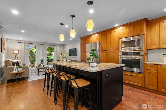 315 10th Ave S Unit 101, Kirkland, WA 98033 - kitchen with stainless steel appliances, brown cabinets, a kitchen island, recessed lighting, and light stone counters